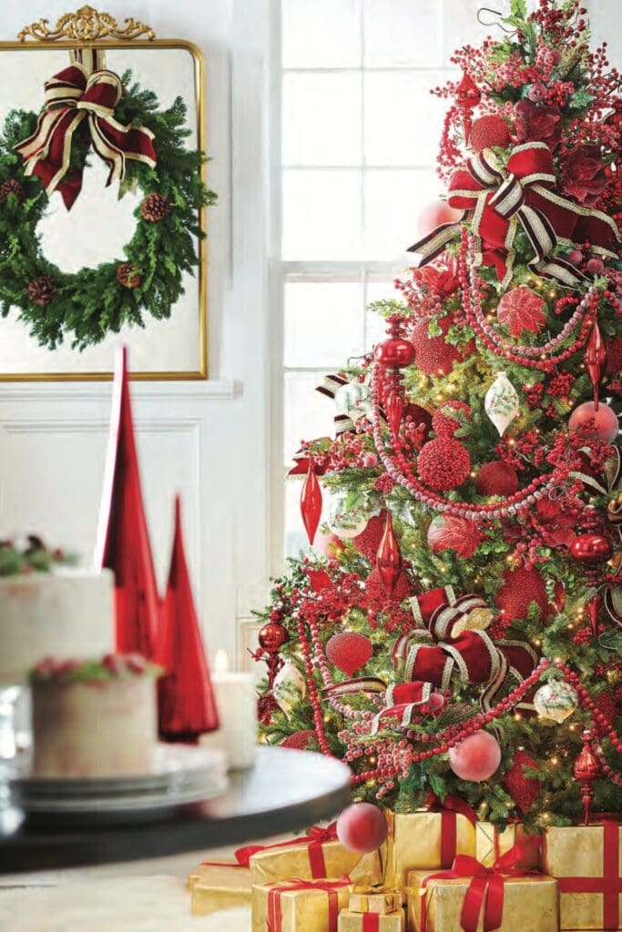 making spirits bright tree, red berry garlands frosted and plain, big bold kribbons, red glass finial, berry balls, red berry picks, holly trimmed ornaments, gold packages wrapped with red ribbon under tree, red glass kismets