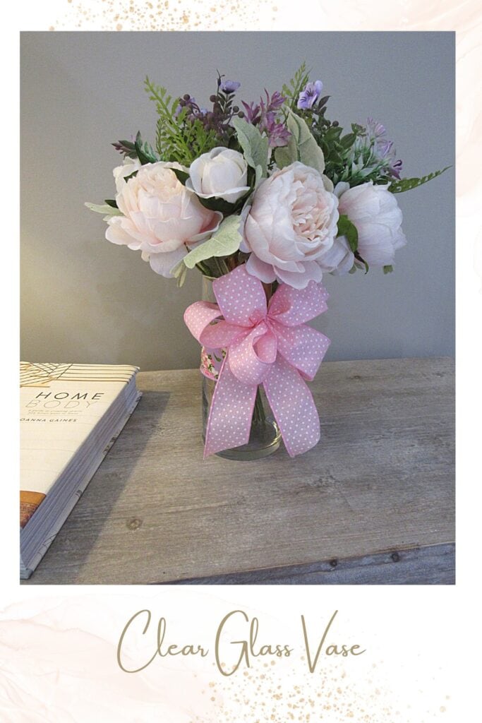 add an artificial flower bouquet to a clear vase and decorate with ribbon