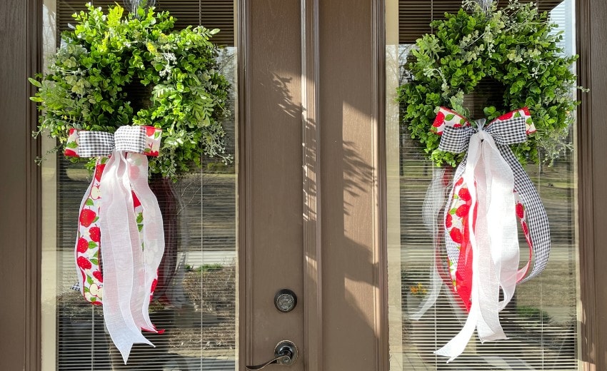 two boxwood wreaths with long-tail bows for double doors