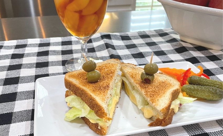 pimento cheese sandwich on plate with pickles and olives