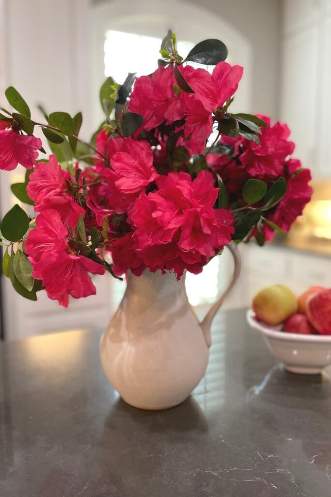 dark pink azaleas in a white stoneware pitcher