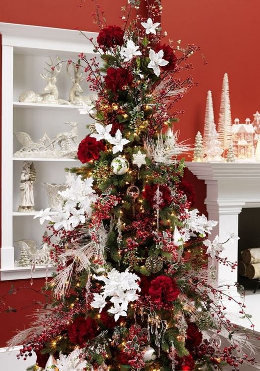 elegant christmas tree with white poinsettias, red berries and pinecones