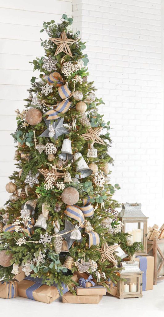 cottage christmas tree with wooden ornaments, natural colored ribbons with light denim, metal stars and big bells, creamy berry picks and garland. Brown paper packages under the tree