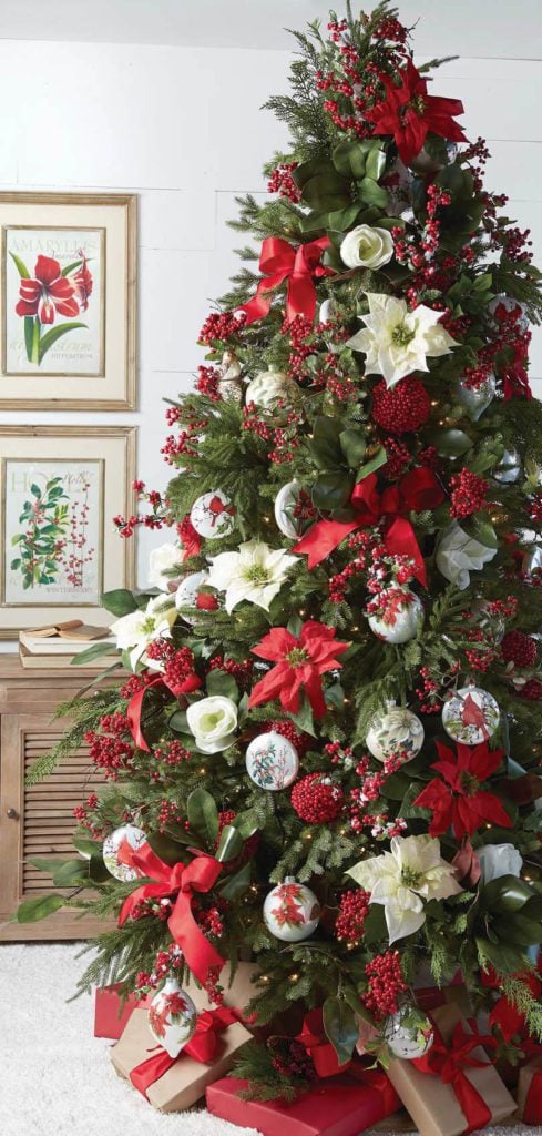 rich red and green christmas tree with lots of red berries, white and red poinsettias, red cardinal ornaments and big red bows