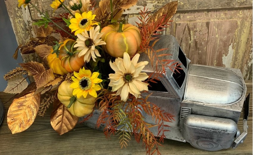 fall floral arrangement in an vintage style truck container, white pumpkins, beige sunflowers, fall greenery