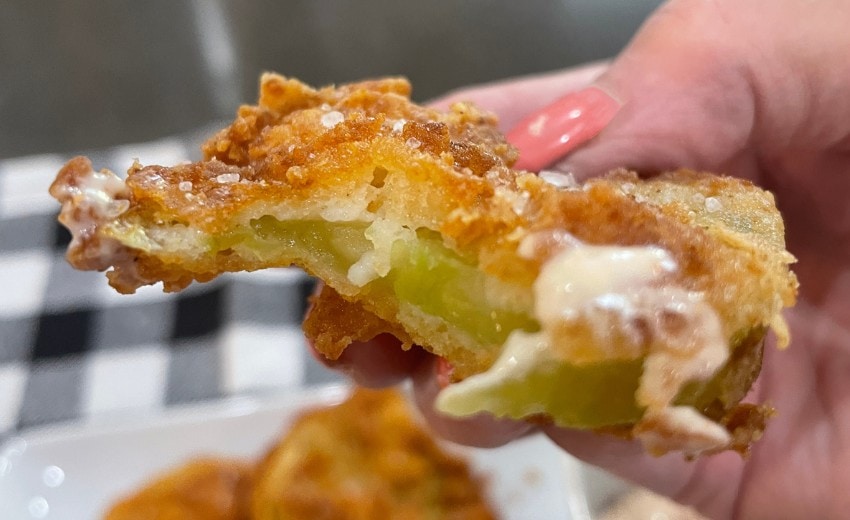 fried green tomato in dipping sauce with a bite taken out