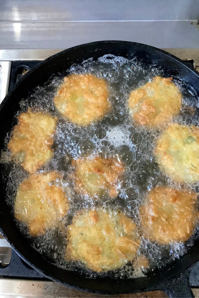 frying battered green tomatoes in a cast iron skillet
