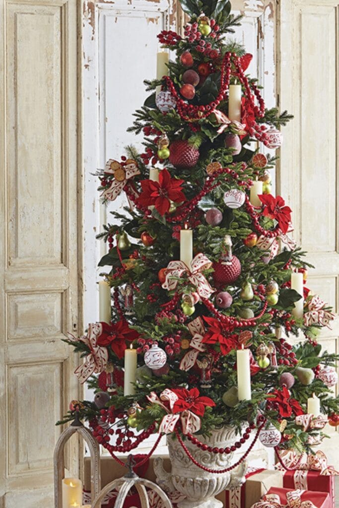 classic red and green christmas tree with white hanging candles, red garland, red berries, frosted fruits, red velvet poinsettias, crabapple garlands.