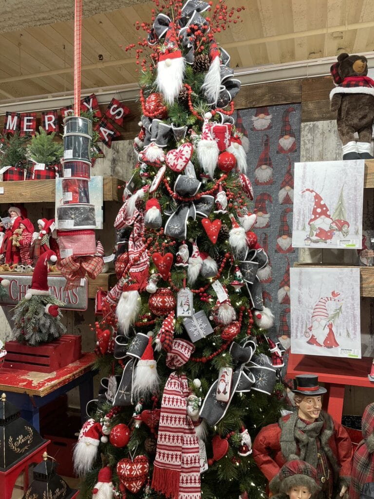 cabin style christmas tree decorated in red and grey, gnome santas, stocking ornaments and scarves, knitted hearts, red wooden garlands and berry picks