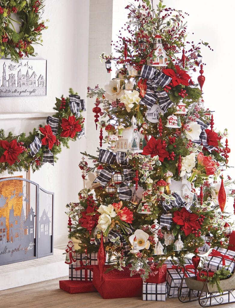 christmas tree with huge red and white poinsettias, church building ornaments, red glass finial and drop ornaments, holly sprays, and bold black and white plaid ribbon