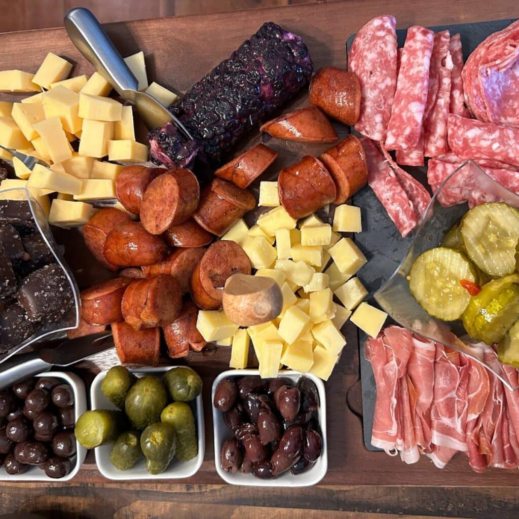 charcuterie board with salami, prosciutto, cheese, smoked sausage, pickles, olives