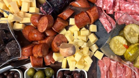 charcuterie board with salami, prosciutto, cheese, smoked sausage, pickles, olives
