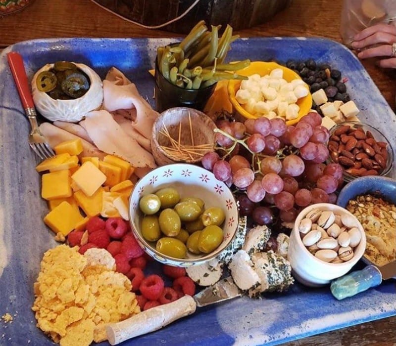 tray with cheeses, olives, fruits, nuts and spreads