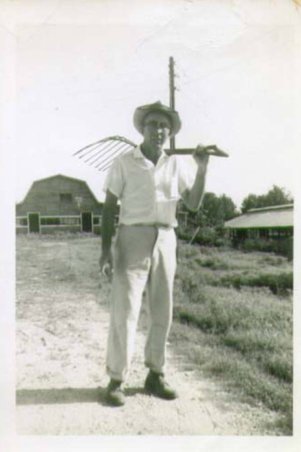 man with pitch fork, barn in background