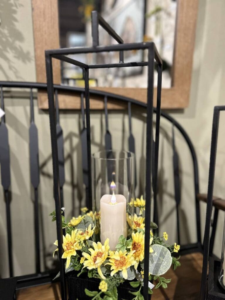 black metal lantern with open sides and bright yellow floral with candle