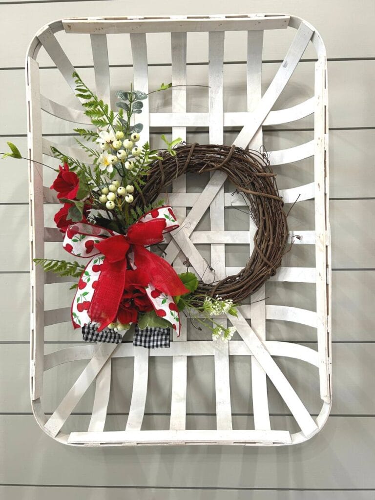 white tobacco basket with a small grapevine wreath, spring floral and a red and white bow