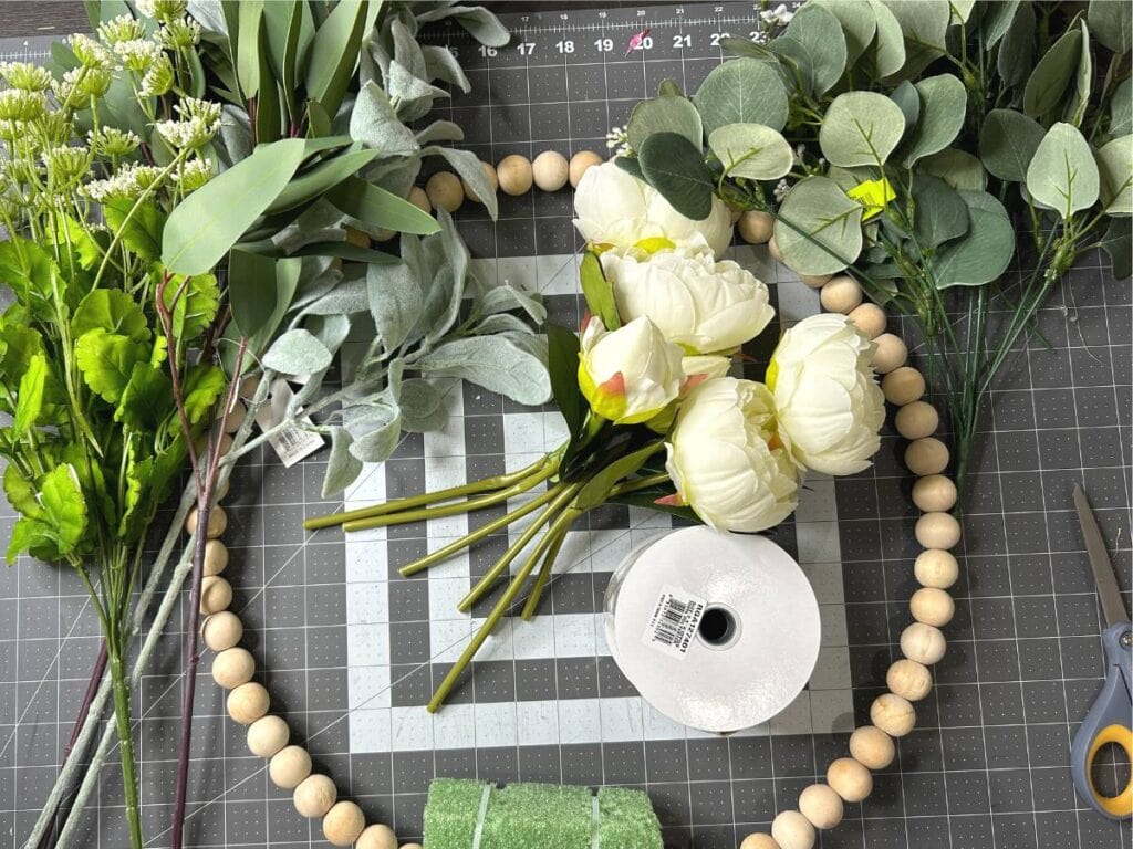 artificial florals, ribbon, and wood bead wreath form