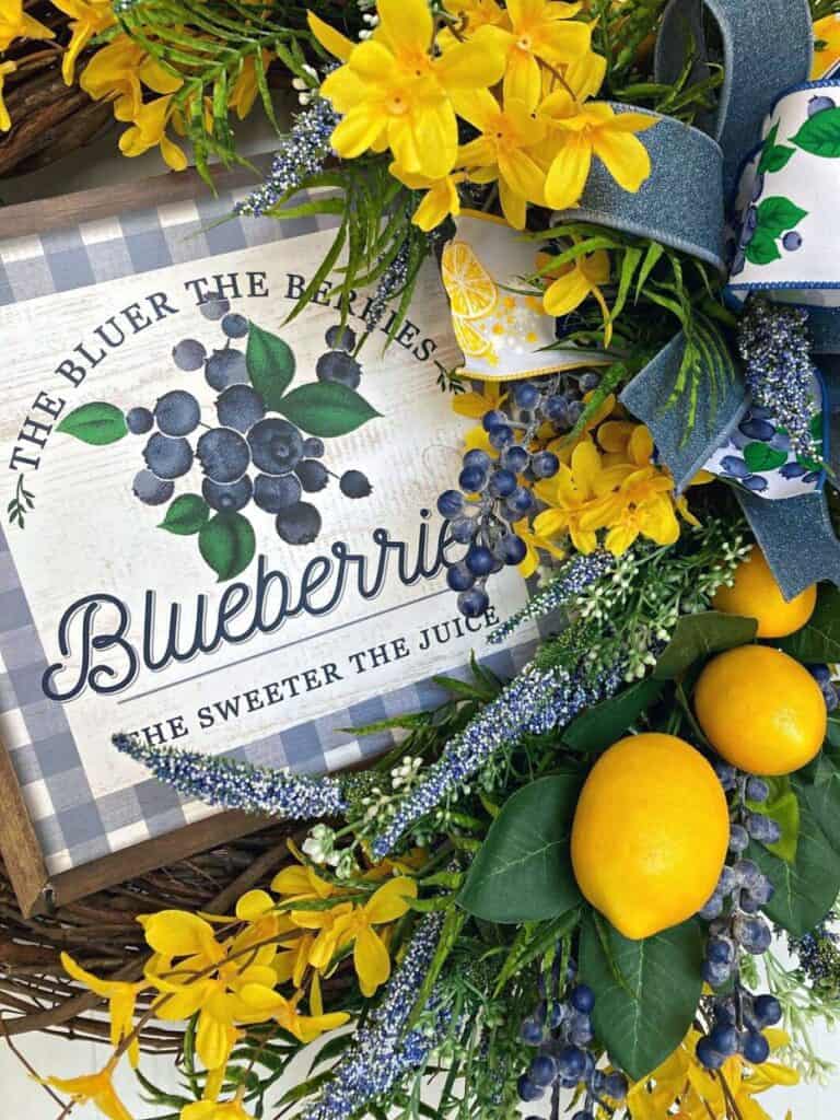 grapevine wreath decorated with blueberries and a blueberry sign, yellow lemons and forsythia