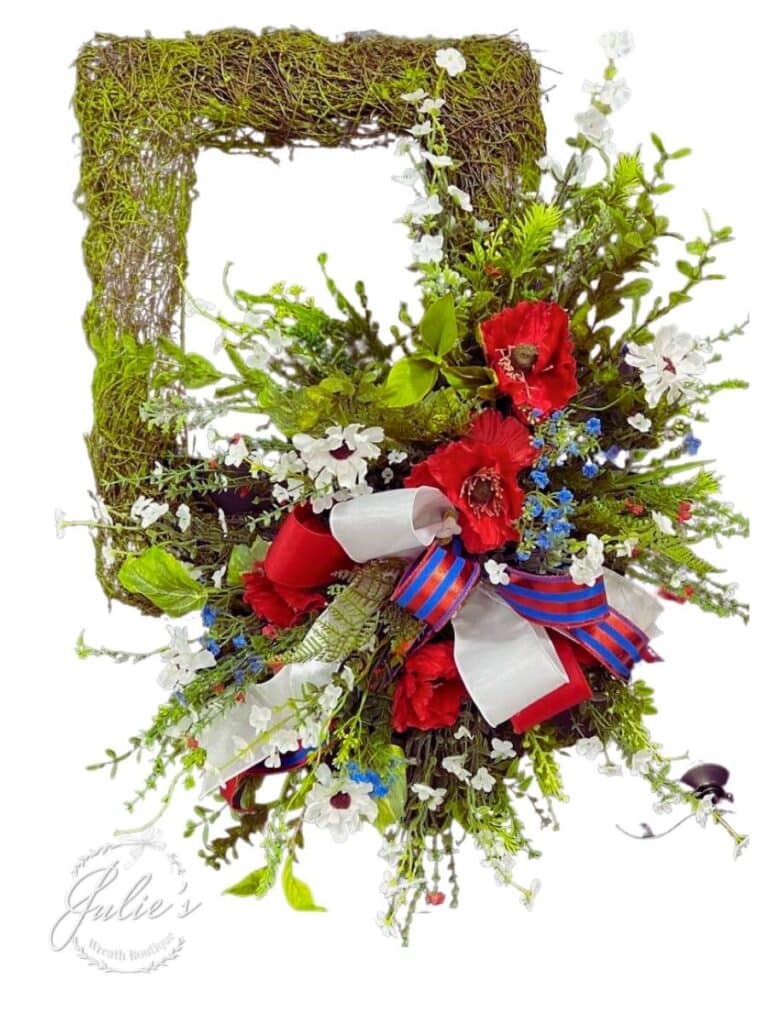 patriotic wreath made with red white and blue flowers on a moss rectangular form