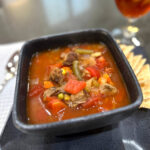 bowl of vegetable beef soup with crackers and tea