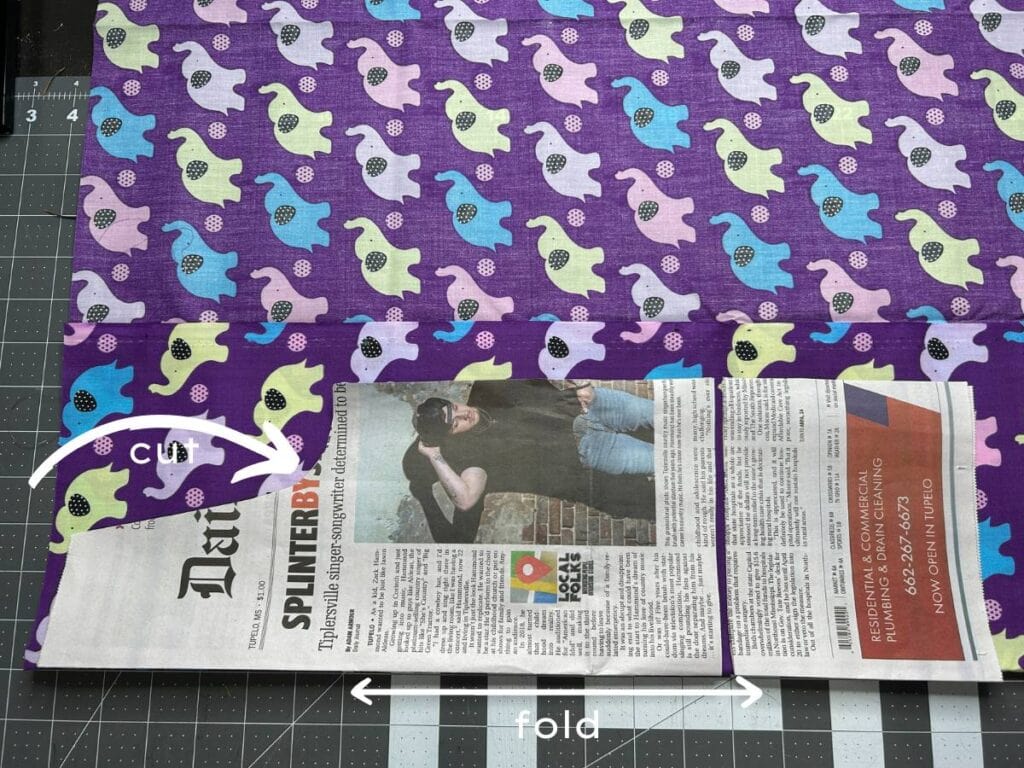 place the newspaper pattern (fold) on the fold of the material, cut around the pattern without cutting the folded side