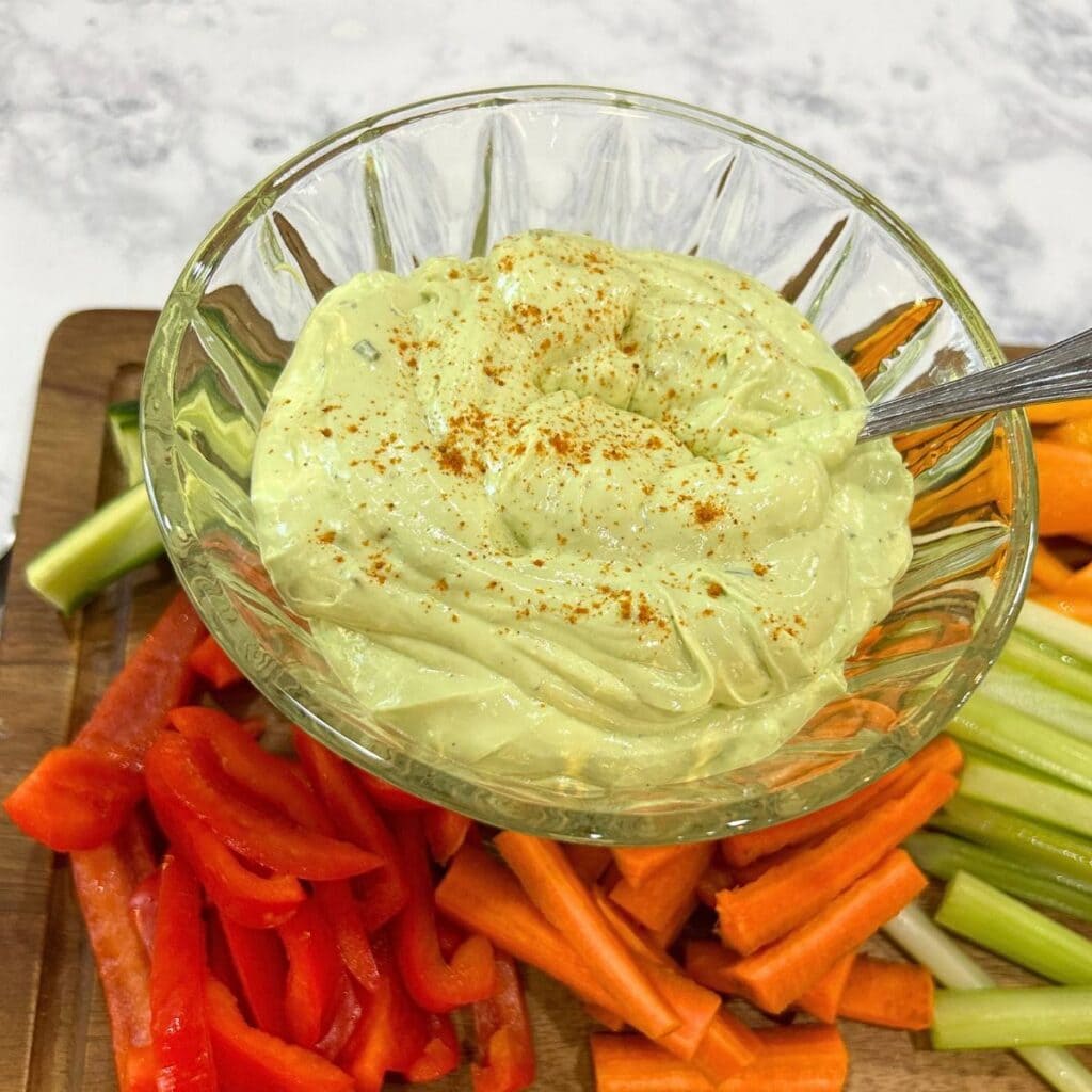 avocado veggie dip on a wooden tray with vegetables