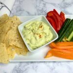 snack plate with avocado veggie dip, chips, pepper strips and cucumber slices