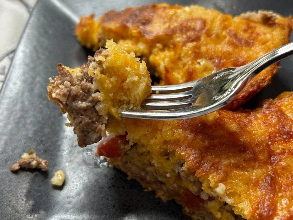 one dish meal cooked in a cast iron skillet, make with cornbread, ground beef, cheddar cheese, onions and rotel