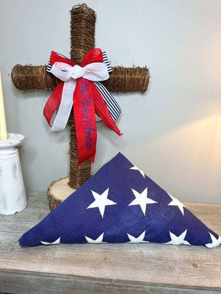 twig cross with patriotic bow on a table with a USA flag