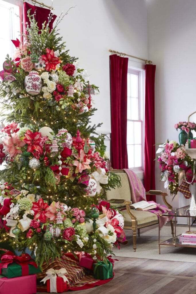 christmas tree decorated with garlands of large flower blooms in red, pink, and light green, roses, poinsettias, and hydrangeas, gold and white ball garlands