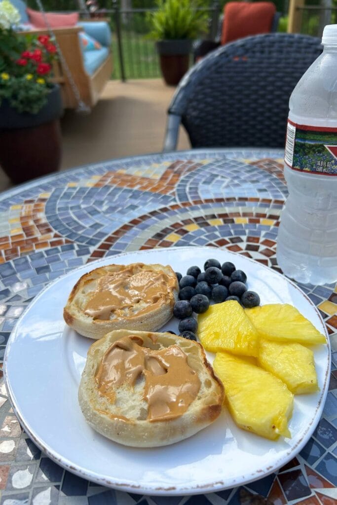 breakfast with bays english muffins spread with peanut butter, fresh blueberries, sliced pineapple and water