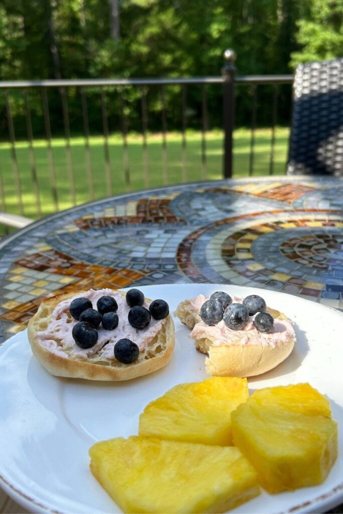 english muffins with whipped strawberry cream cheese, blueberries and fresh pineapple on back porch