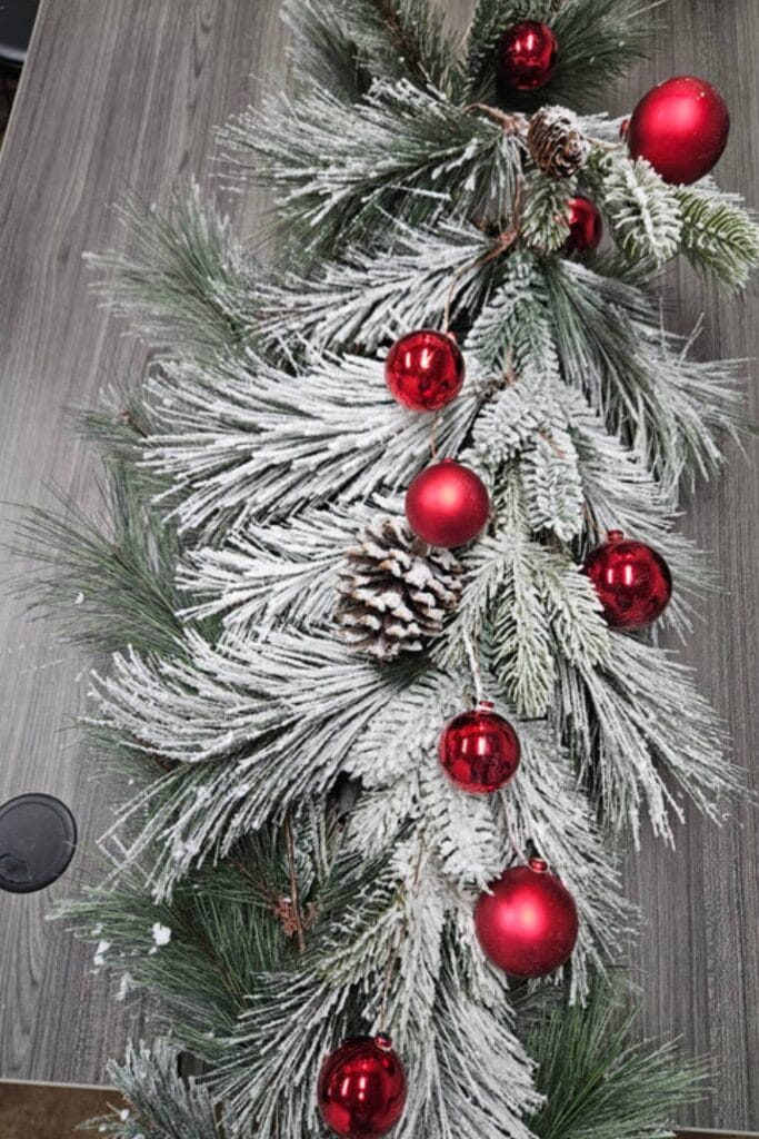 frosted evergreen garland with red balls and pinecones