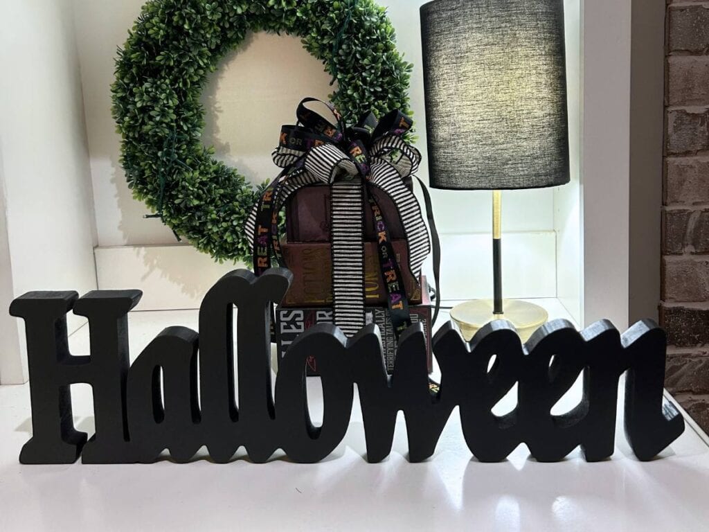 black halloween sign sitting on a bookcase