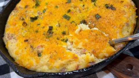 cheesy grits with ham cooked in a cast iron skillet