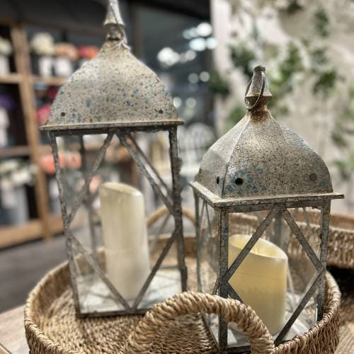 metal and glass lanterns sitting on a wicker tray