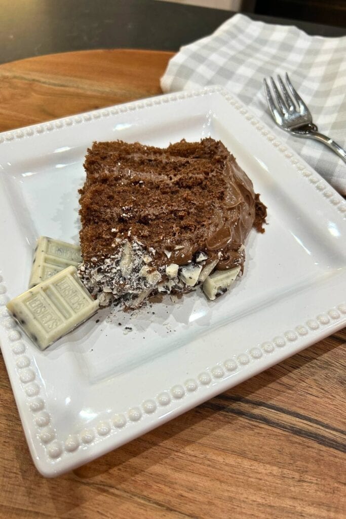 slice of chocolate cake with crumbled Hershey's cookies and cream candy bar on top