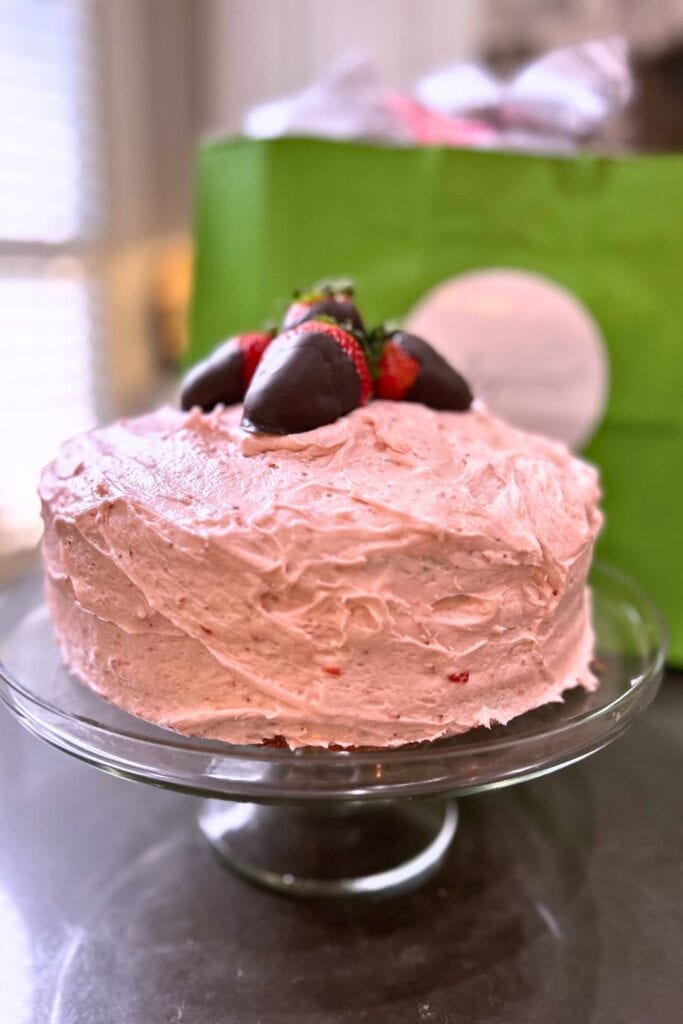strawberry pink lady cake with chocolate covered strawberries on top
