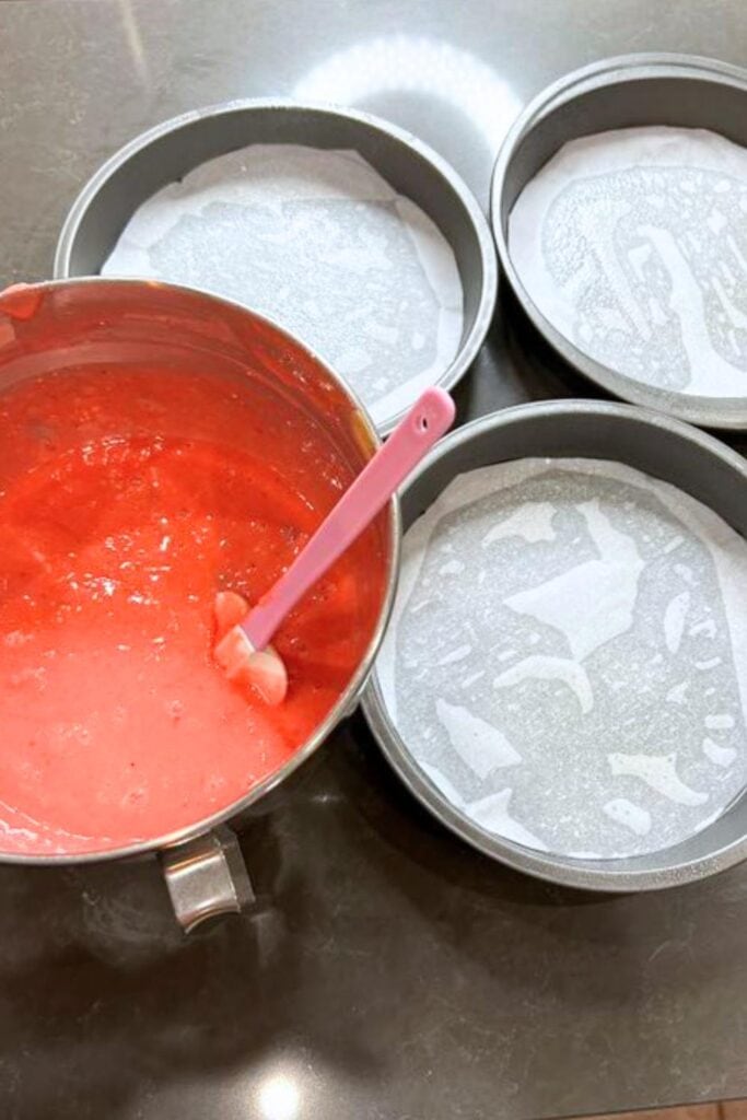 strawberry cake batter divided among three cake pans
