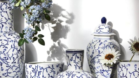 collection of white and blue pottery, some sitting on a stack of books as a riser