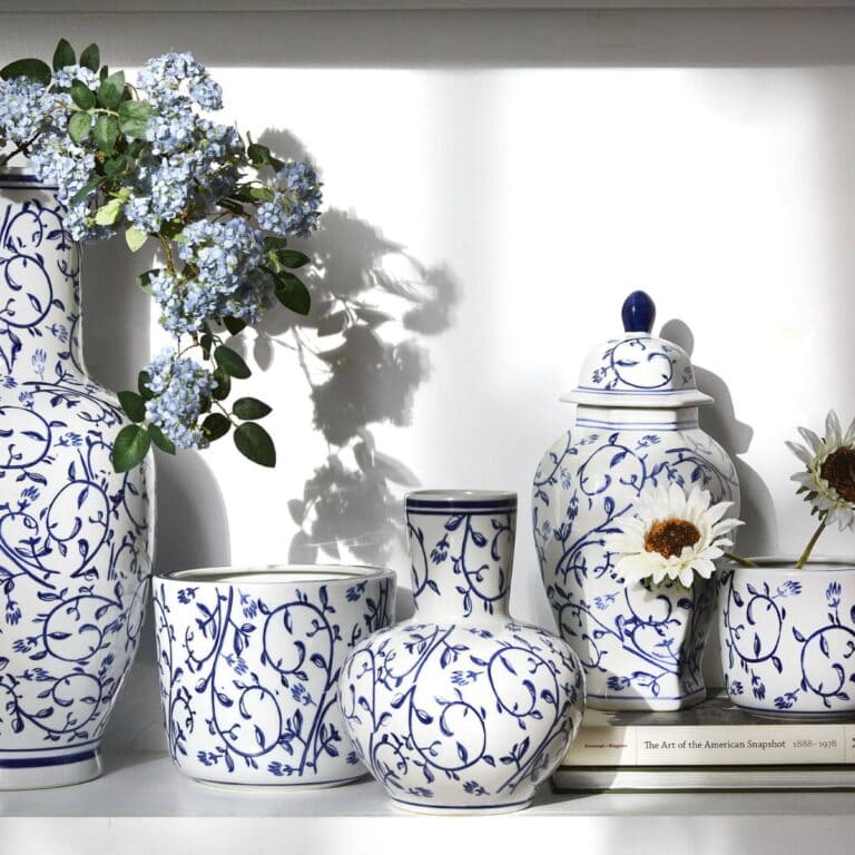 collection of white and blue pottery, some sitting on a stack of books as a riser