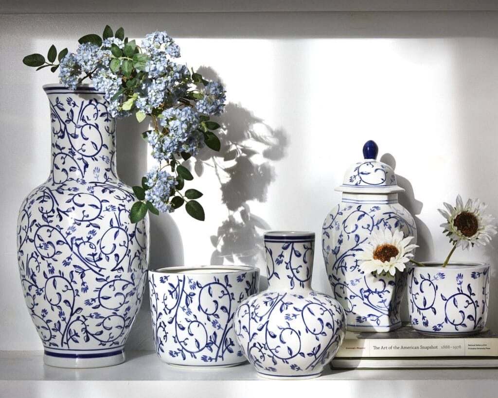 collection of white and blue pottery, some sitting on a stack of books as a riser