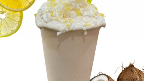 lemony coconut protein smoothie topping with whipped cream, coconut and lemon zest