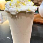 lemony coconut protein smoothie topped off with whipped cream, coconut, and lemon zest
