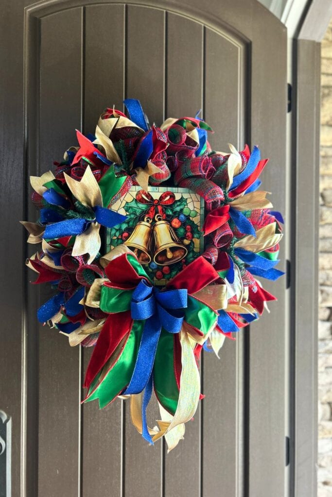 red, green, gold, and blue deco mesh Christmas wreath with an exclusive Trendy Tree jingle bells stained glass look metal sign