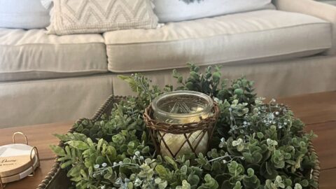 unique ideas for displaying wreaths indoors, mixed boxwood greenery wreath inside a wooden tray on a coffee table, with candle in the center