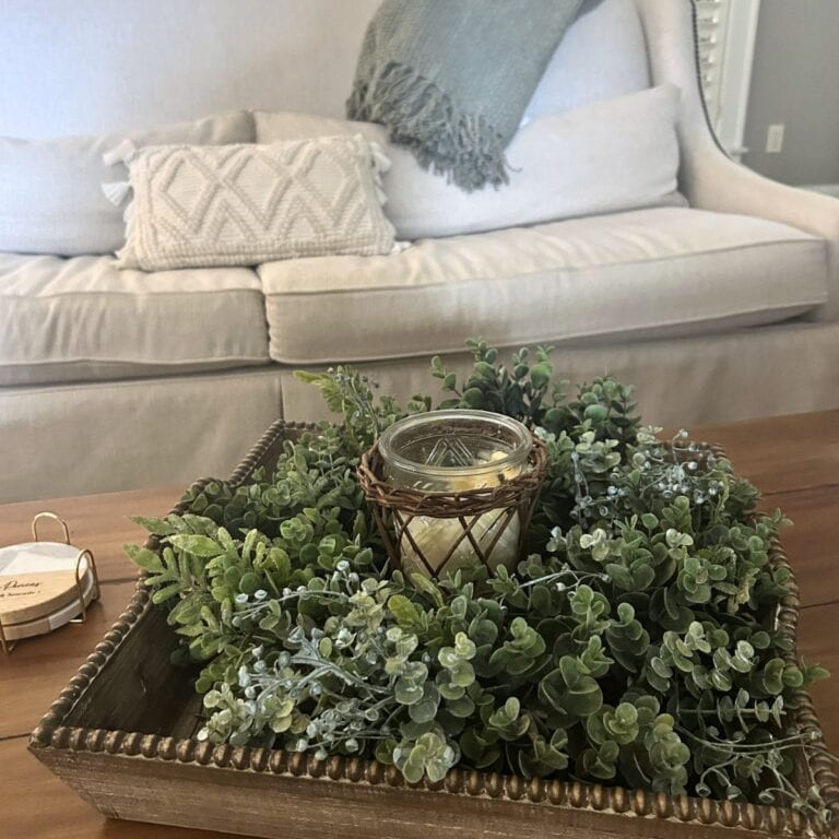 unique ideas for displaying wreaths indoors, mixed boxwood greenery wreath inside a wooden tray on a coffee table, with candle in the center