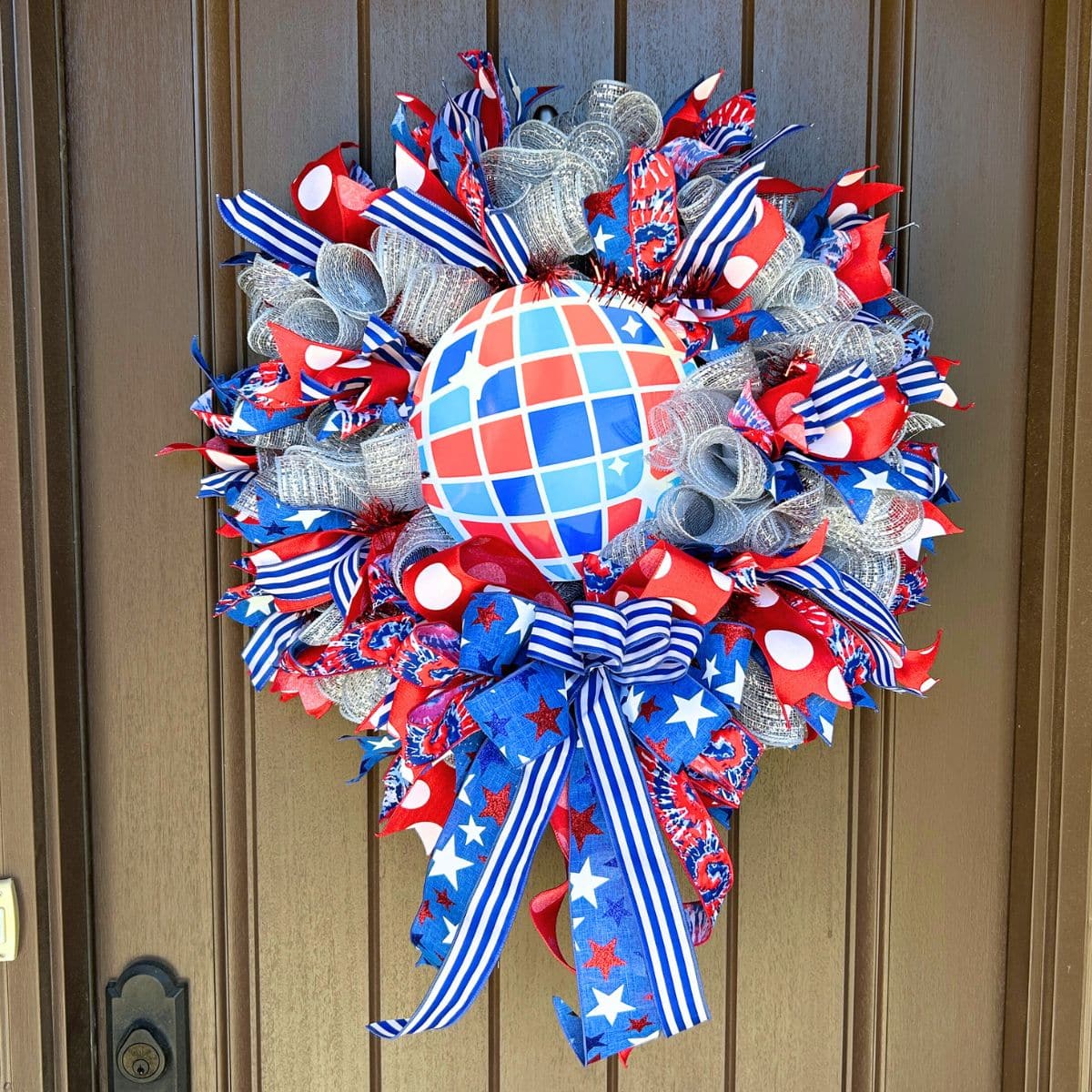 patriotic mesh wreath in red white and blue with a round disco ball style sign