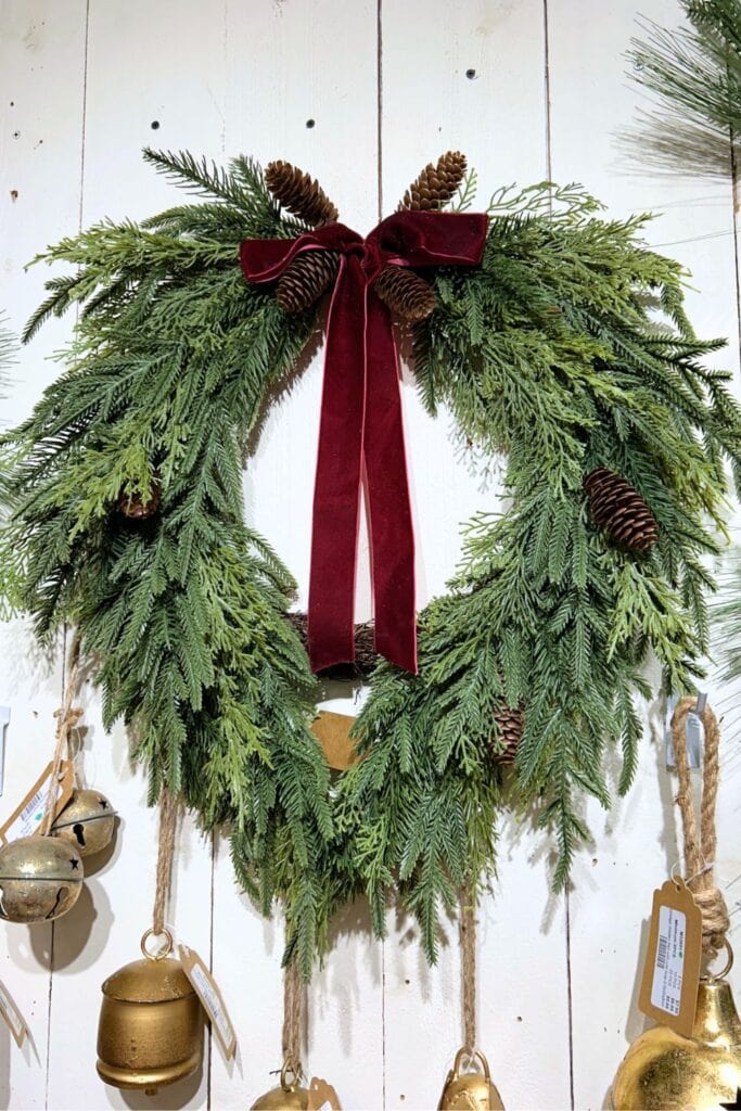 draped greenery wreath with small pinecones and droopy velvet ribbon