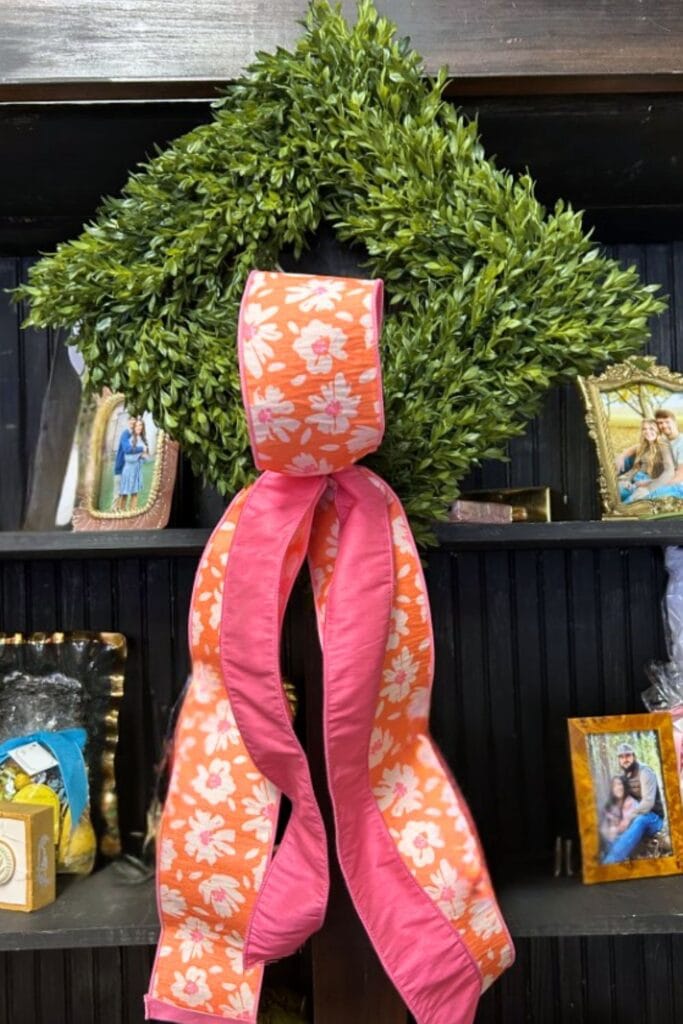 boxwood wreath turned diamond shaped with pink and orange ribbon loosely tied